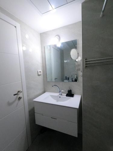 a white bathroom with a sink and a mirror at Beach Suite Israel - Indoor Pool, Best View, Gym, Massage Chair, Spa ביץ סוייט ישראל - נוף ים מאלף, בריכה מקורה, כיסא מסאז, חדר כושר וספא in Ashqelon