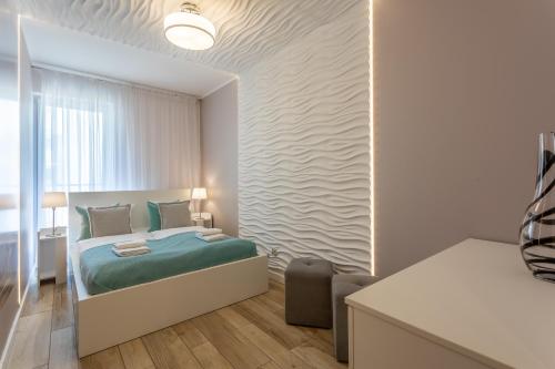 een slaapkamer met een bed met blauwe lakens en een raam bij Ambria Apartments Ułańska in Świnoujście