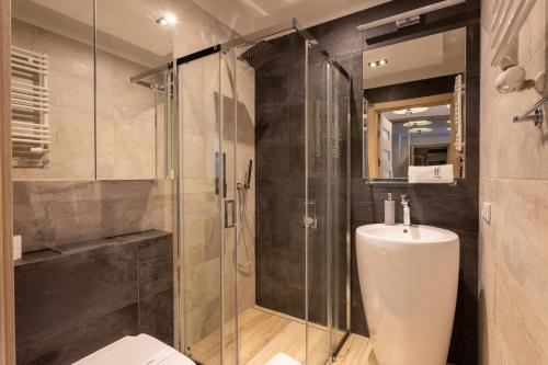 een badkamer met toilet en glazen douche bij Ambria Apartments Ułańska in Świnoujście