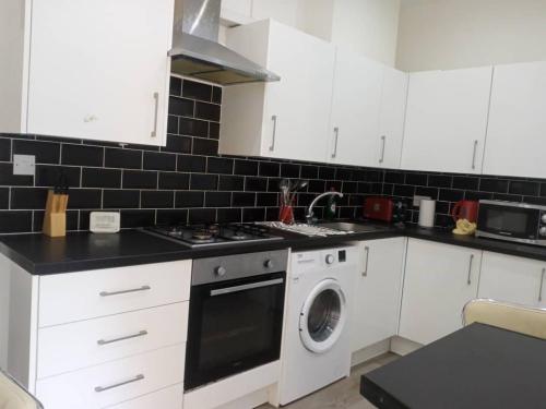 a kitchen with white cabinets and a washing machine at Double-bed (H2) close to Burnley city centre in Burnley
