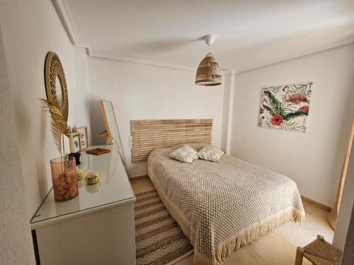 a small bedroom with a bed and a table at Ático Pola in Santa Pola