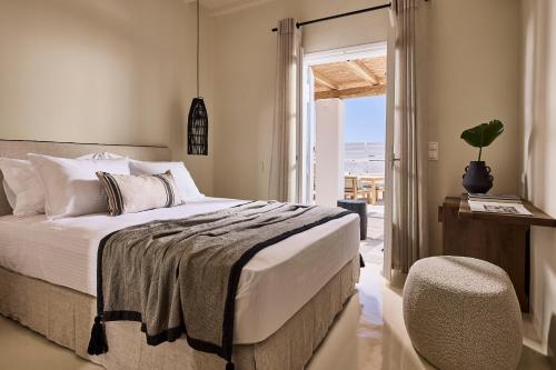 een slaapkamer met een bed, een stoel en een raam bij Sharm Hotel Mykonos in Mykonos-stad