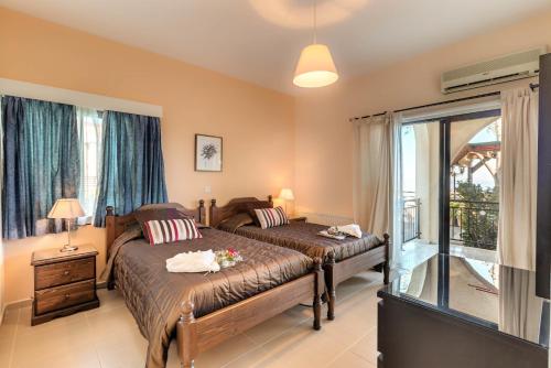 a bedroom with two beds and a balcony at Hill View Hotel Apartments in Pissouri