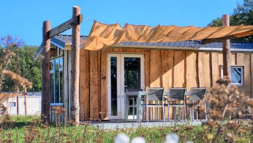 ein Holzhaus mit Stühlen davor in der Unterkunft Hoeve Twente - Bosuil in Heythuysen