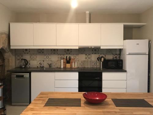 a kitchen with white cabinets and a wooden table at Maison de la Combe in Domme