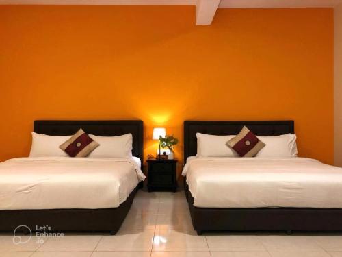 two beds in a room with an orange wall at Malacca City Center Town House by 360HOME in Melaka