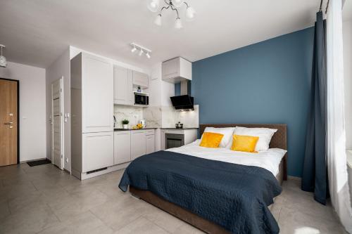 a bedroom with a blue wall and a bed with orange pillows at AYCON APARTMENTS - MODERN SPACE in Warsaw