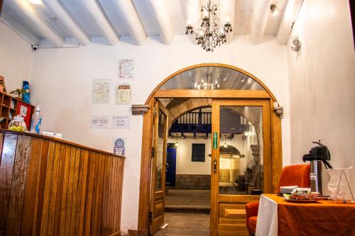 Habitación con puerta, mesa y lámpara de araña. en Estancia San Pedro Hotel, en Cusco