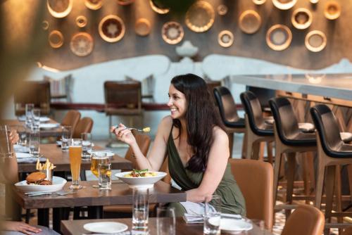 a woman sitting at a table eating food in a restaurant at Hotel Contessa - Suites on the Riverwalk in San Antonio