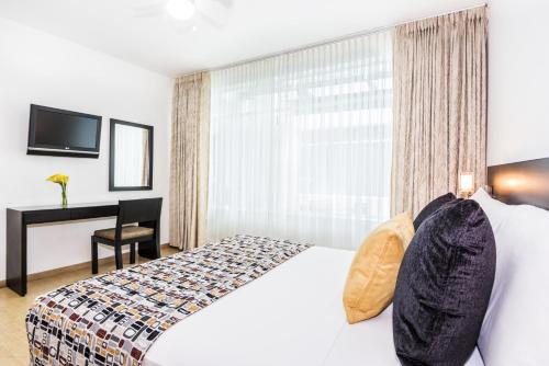 a bedroom with a bed and a desk and a window at Hotel Asturias Medellin in Medellín