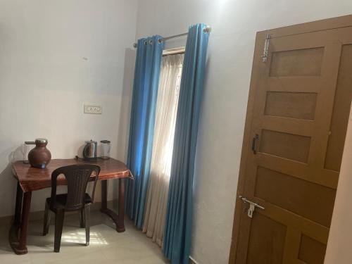 a room with a table and a door and a table and chair at Rose Garden home stay Thrissur in Trichūr