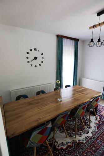 a dining room with a wooden table and a clock on the wall at Villa Sara on river Una in Bihać