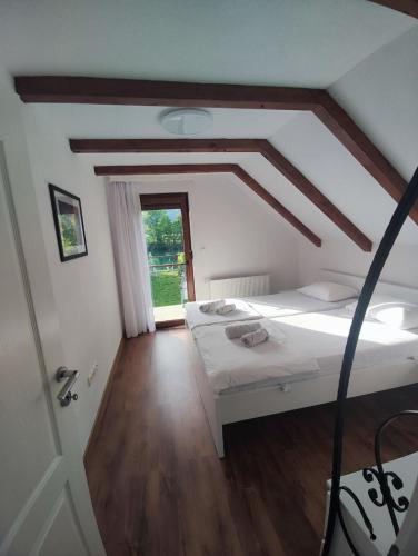a bedroom with a white bed and a wooden floor at Villa Sara on river Una in Bihać