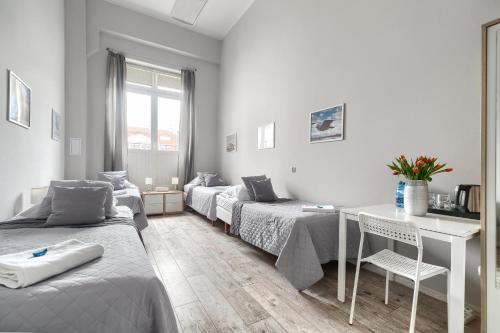 a room with three beds and a desk and a table at Stawa Villa & Apart in Świnoujście