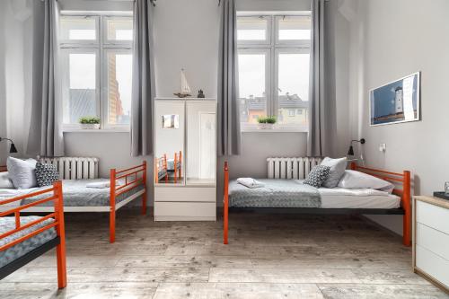 a bedroom with two beds and two windows at Stawa Villa & Apart in Świnoujście