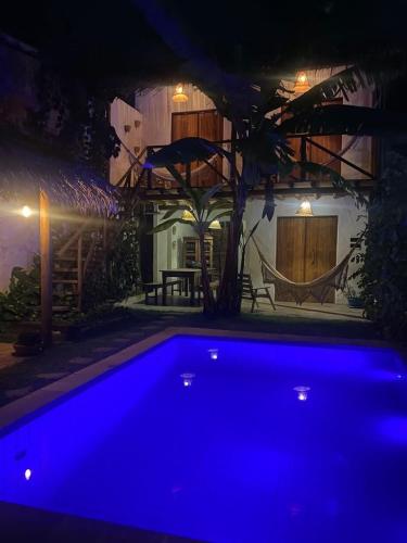 una piscina azul frente a una casa por la noche en Pousada Vila do Alto, en Japaratinga