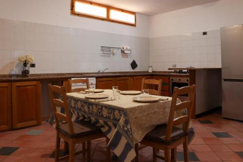a kitchen with a table with chairs and a refrigerator at Taverna Porto Conte in Porto Conte