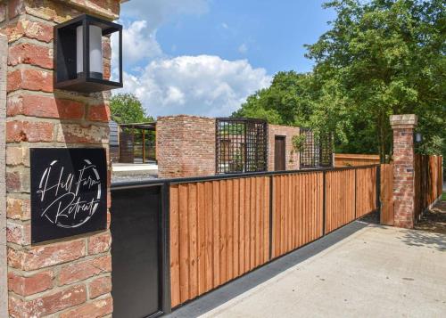 una valla de madera con una puerta y un edificio de ladrillo en Hill Farm Retreat en Wangford