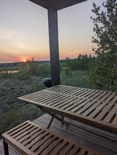 a wooden picnic table on a porch with the sunset in the background at Cozy house with sauna by the lake in Lokuti