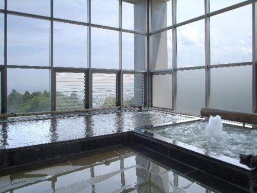 a bath tub with water in a room with windows at Kannawa Onsen Zekkei no Yado Sakuratei - Vacation STAY 50714v in Beppu
