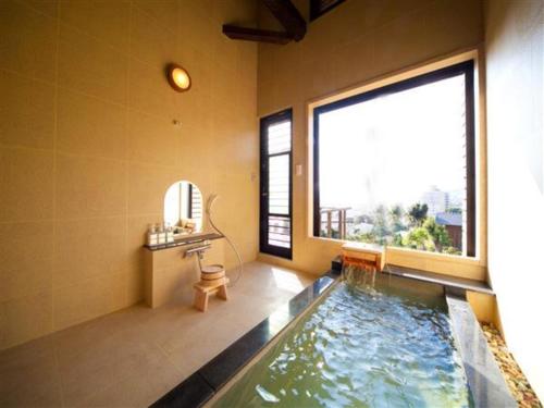 a bathroom with a swimming pool with a large window at Kannawa Onsen Zekkei no Yado Sakuratei - Vacation STAY 50727v in Beppu