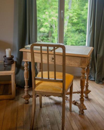 a wooden table with a chair and a wooden table with a window at Domaine de La Soudelle in Chanceaux-sur-Choisille