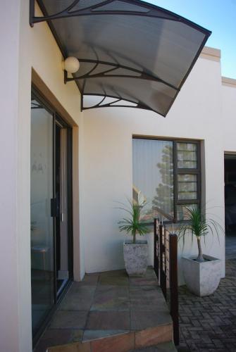 awning on the side of a building with two potted plants at The Third Dolphin in Herolds Bay