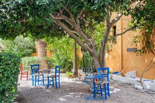 a group of blue chairs and tables under a tree at Vagia Traditional, Aegina Island in Vaia