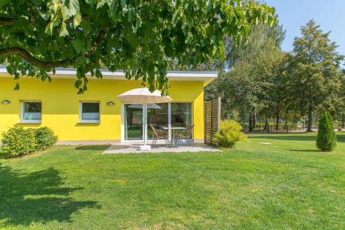 a yellow house with a table and an umbrella at Bungis Am Grimnitzsee in Joachimsthal