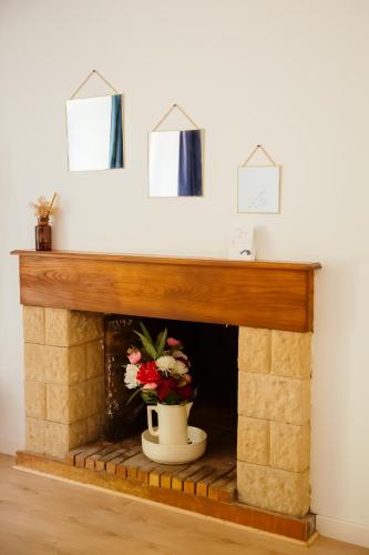 a fireplace with a vase with flowers in it at La Borgnardais gîte en Brocéliande, proche Guer - 1 à 11 couchages in Loutehel