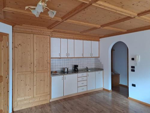 a kitchen with white cabinets and a wooden ceiling at Appartamenti Col da Vënt in Corvara in Badia