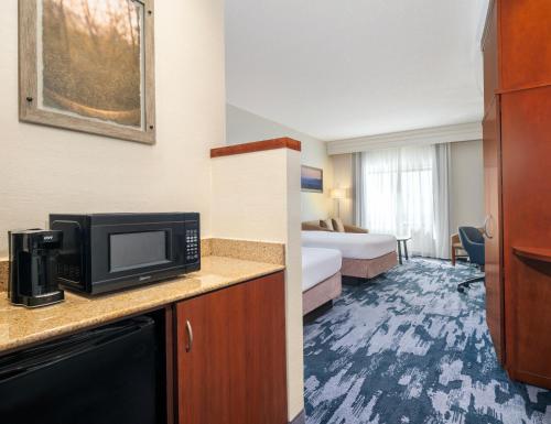 a hotel room with a bedroom with a bed and a microwave at Fairfield Inn & Suites Orlando Ocoee in Orlando