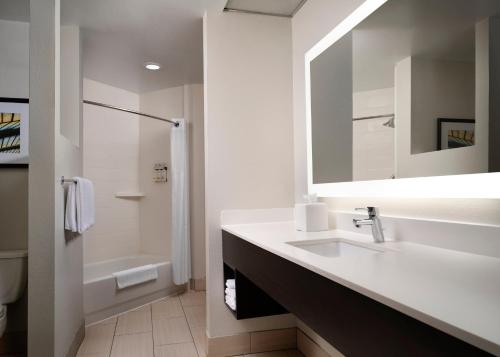 a white bathroom with a sink and a mirror at Holiday Inn Express and Suites New Orleans Airport by IHG in Saint Rose