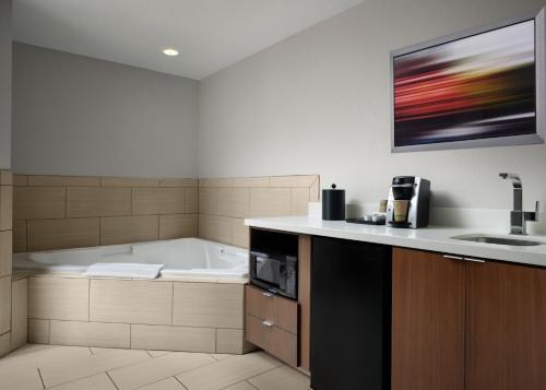a bathroom with a bath tub and a sink at Holiday Inn Express and Suites New Orleans Airport by IHG in Saint Rose