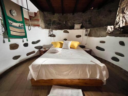 a bedroom with a bed in a stone wall at Moinho do Monte Branco in Castro Verde