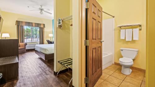 a bathroom with a toilet and a bed and a tub at Magnuson Hotel Wildwood Inn Crawfordville in Crawfordville