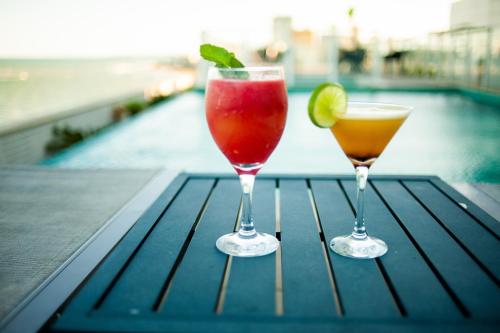 two cocktails sitting on a table next to a pool at Paradiso Macae Hotel in Macaé