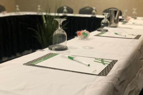 a table with a white table cloth with a bottle and a pen at Holiday Inn Toledo - Maumee I-80/90 by IHG in Maumee