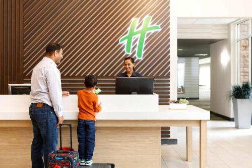 a man and a young boy standing at a reception desk at Holiday Inn Toledo - Maumee I-80/90 by IHG in Maumee