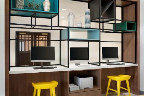 a desk with two monitors and two yellow stools at Holiday Inn Toledo - Maumee I-80/90 by IHG in Maumee