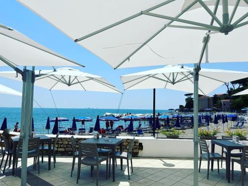 un patio avec des tables et des parasols et l'océan dans l'établissement Seahouse Bocca di Magra, à Bocca di Magra