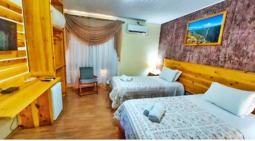 a hotel room with two beds and a desk at Pousada Encanto dos Cânions in Cambara do Sul