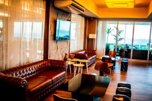 a living room with a leather couch and a television at Paradiso Macae Hotel in Macaé