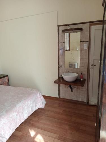 a bedroom with a bed and a sink and a mirror at Hotel Mallorca in Mendoza