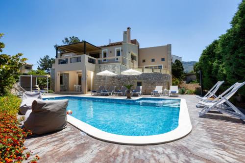 a villa with a swimming pool in front of a house at Palladio Luxury Villa in Roussospítion