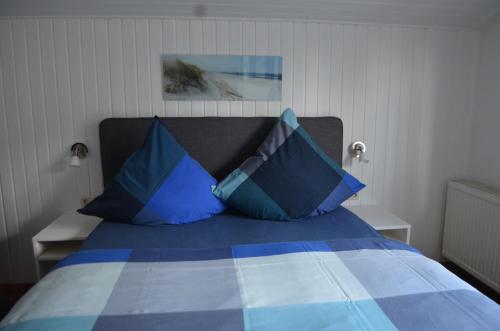 a bedroom with a bed with blue pillows at Jolle im Schiffehaus in Wangerland