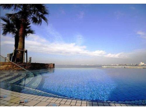 a large swimming pool with a palm tree and water at Hotel Sunlife Garden - Vacation STAY 55409v in Hiratsuka