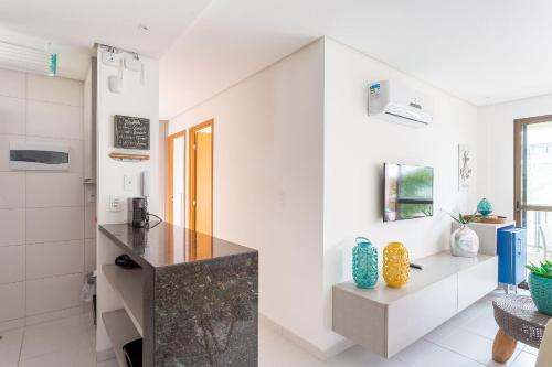 a kitchen with white walls and a black counter at CoHost Flat BeachClass EcoLife 104G in Porto De Galinhas