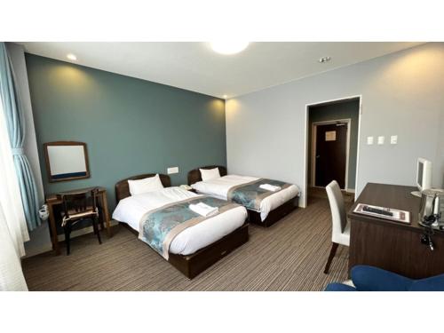 een hotelkamer met 2 bedden en een bureau bij Tsukioka Onsen Furinya - Vacation STAY 55986v in Shibata