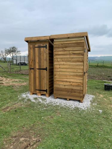 a wooden outhouse sitting in the middle of a field at Tal-y-fan farm 6m stargazer tent in Bridgend